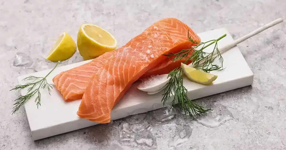 Rå superior laksefilet fra norske fjorder på marmorfjøl med sitron og dill